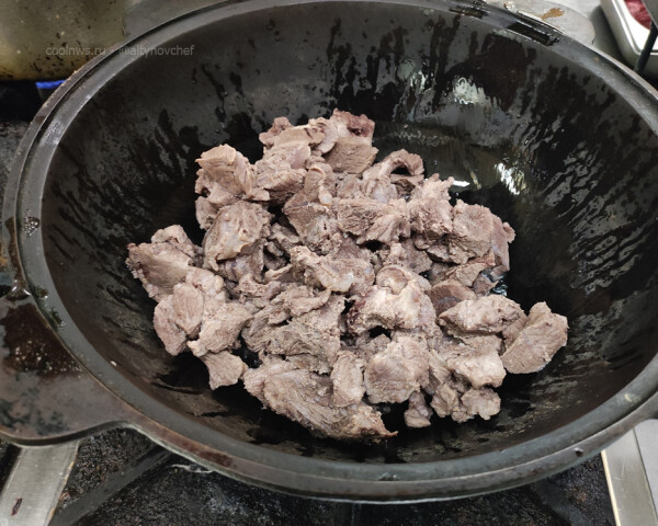 Перекладываем подваренное мясо кабана в разогретый казан. Обжариваем мясо на сильном огне 2-3 минуты.