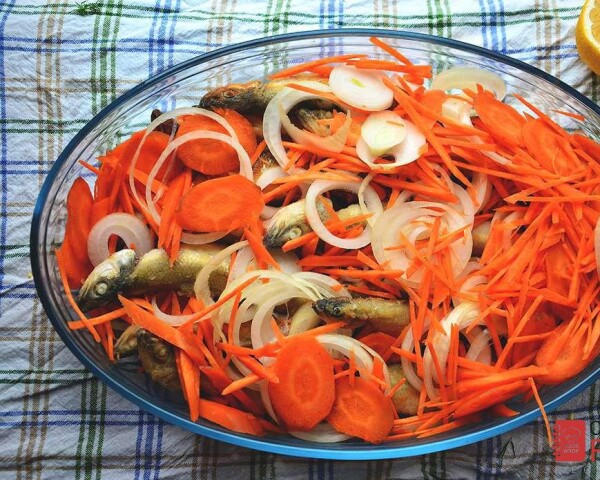 По верх рыбы уложить остальные кольца сырого лука и моркови.