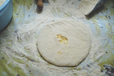 Далее раскатываем скалкой и делаем в центре дырочку. Выкладываем хачапури на смазанный маслом протвень.