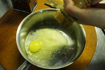 Затем делаем яично-сырный соус: трем на мелкой терке сыр пармезан. Кладем его в сотейник, добавляем яйца и немного мелем черного перца...