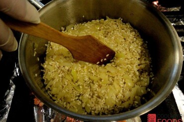 обжариваем до полуготовности репчатый лук, затем добавляем рис арборио... ... и перемешиваем с репчатым луком,  Обжариваем рис до тех пор, пока рис не станет коричневатым и не будет пощелкивать.