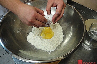 За это время приготовим тесто для бежбармака. В миске делаем горку муки, добавляем щепотку соли и в центр кладем яйцо.